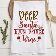 a dish towel with the words deer santa just bring wine on it next to a wooden spoon