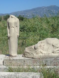 two stone statues sitting next to each other on top of a cement slab in the grass