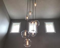 a chandelier hanging from the ceiling in a room with three windows and no curtains