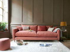 a living room with a pink couch and white rug on the floor next to a window