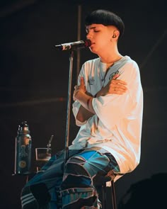 a young man sitting on top of a stool next to a microphone