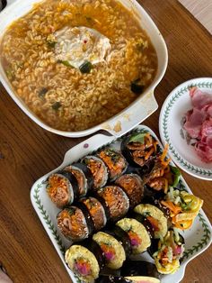 an assortment of sushi and rice dishes on a wooden table with chopsticks