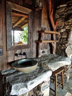 a rustic bathroom with stone walls and wood trimmings is featured in this image