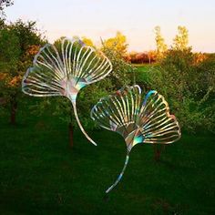 two metal sculptures sitting on top of a lush green field