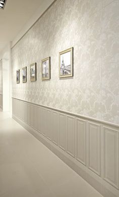 an empty hallway with white walls and pictures on the wall