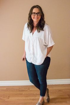 a woman standing in front of a wall with her hands on her hips and smiling