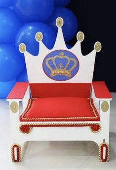 a toy chair with a crown on it sitting in front of blue and white balloons