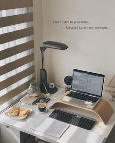 a laptop computer sitting on top of a white desk next to a cup of coffee