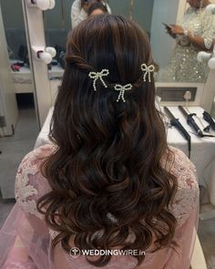 the back of a woman's head with long wavy hair and bows in it