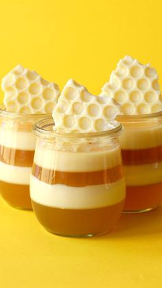 three desserts in small glass jars with whipped cream on top and caramel sauce below