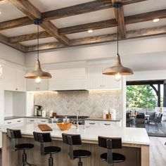 a kitchen with an island and bar stools in front of the countertop area