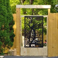 the gate is made out of wood and has an iron tree design on it's side