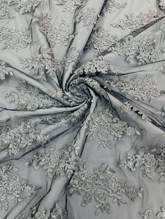 an image of a fabric with flowers and leaves on the side, in grey color