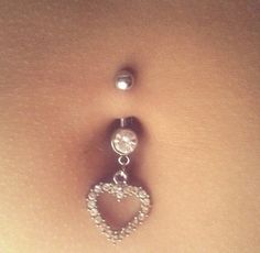 a belly ring with a heart shaped bead hanging from it's back end