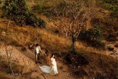 a bride and groom walking down a dirt path