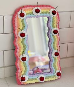 a colorful mirror with cherries hanging from it