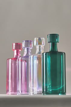 five different colored glass bottles lined up on a counter top with one empty bottle in the middle