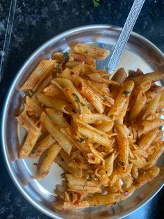 a silver bowl filled with pasta on top of a table