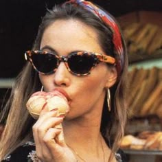 a woman eating a doughnut while wearing sunglasses