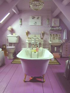 an old fashioned bathtub in a purple bathroom with chandelier and toiletries