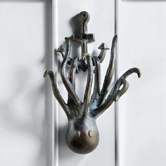 a metal hook on the side of a white door with an iron sculpture hanging from it's center