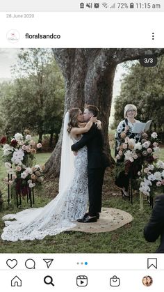 a bride and groom kissing under a tree in front of their wedding ceremony altars