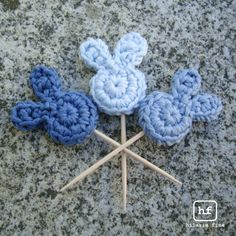 crocheted blue and white flowers on top of a granite surface with wooden sticks