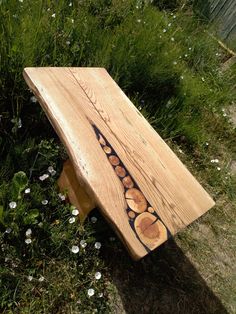 a wooden bench sitting on top of a lush green field next to flowers and grass