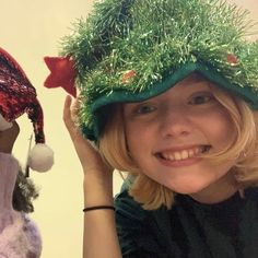 a woman wearing a green hat next to a stuffed animal with decorations on it's head