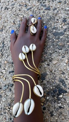 A stunning bracelet featuring multiple cowry shells, beautifully arranged on elegant brass wires that wrap around the wrist with fluidity and grace. Inspired by natural forms, this design captures the essence of African heritage, combining tradition and modern sophistication. "Kipepeo" is a Swahili word that means "butterfly." It symbolizes transformation, beauty, and freedom, making it a fitting name for a piece that has a light, organic flow, like the design of the bracelet. Gold Hand Wrapped Jewelry For The Beach, Beach Gold Hand Wrapped Jewelry, Adjustable Brass Bracelets For The Beach, Gold Brass Bracelet For The Beach, Gold Brass Bracelets For The Beach, Handmade Brass Bracelets For Beach, Handmade Gold Shell-shaped Bracelets, Handmade Gold Shell-shaped Bracelet, Unique Beach Bangle Jewelry