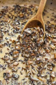 a wooden spoon is stirring some food in a pan with mushrooms and other things on it