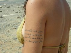 the back of a woman's body with arabic writing on her arm and chest