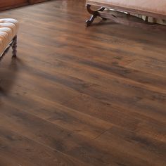 a wooden floor with a bench and chair next to it in a living room area