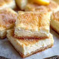 three pieces of dessert sitting on top of a silver tray next to lemons and a fork