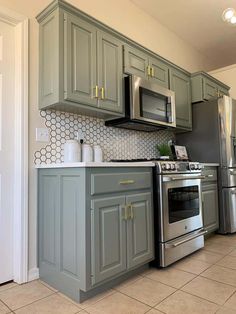 a kitchen with gray cabinets and stainless steel appliances, including a silver stove top oven