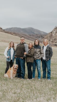 a group of people standing next to each other in a field with a brown dog