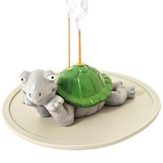 a small toy turtle on top of a green object with two sticks sticking out of it's shell