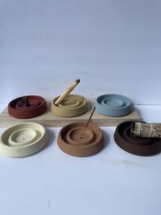 four bowls with yarn in them sitting on top of a wooden stand next to each other