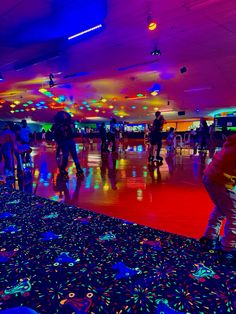 many people are skateboarding and having fun at the bowling alley with colorful lights on the ceiling