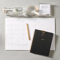 a desk with a notepad, pen and glasses on it next to a bottle of water