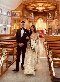 a man and woman standing in front of pews at a church together, posing for the camera