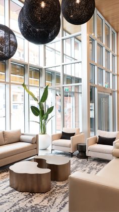 a living room with couches, chairs and tables in front of large glass windows