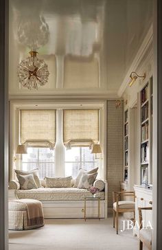 a living room filled with furniture and windows covered in roman blind shades on top of them