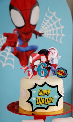 a spiderman birthday cake with the number six on it and some decorations around it