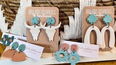 three pairs of earrings are on display in front of some baskets with cards and tags