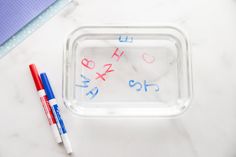 a plastic container with writing on it next to two markers