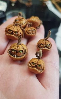 small pumpkins with green eyes are being held by someone's hand