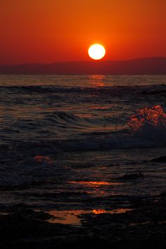 the sun is setting over the ocean with waves