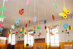 some paper flowers and ladybugs hanging from the ceiling in a room with windows