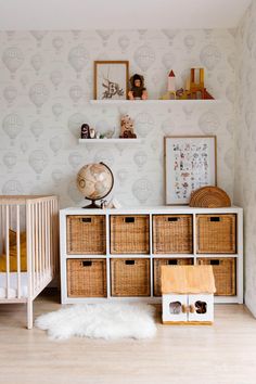 a baby's room with a crib, toy chest and wallpaper